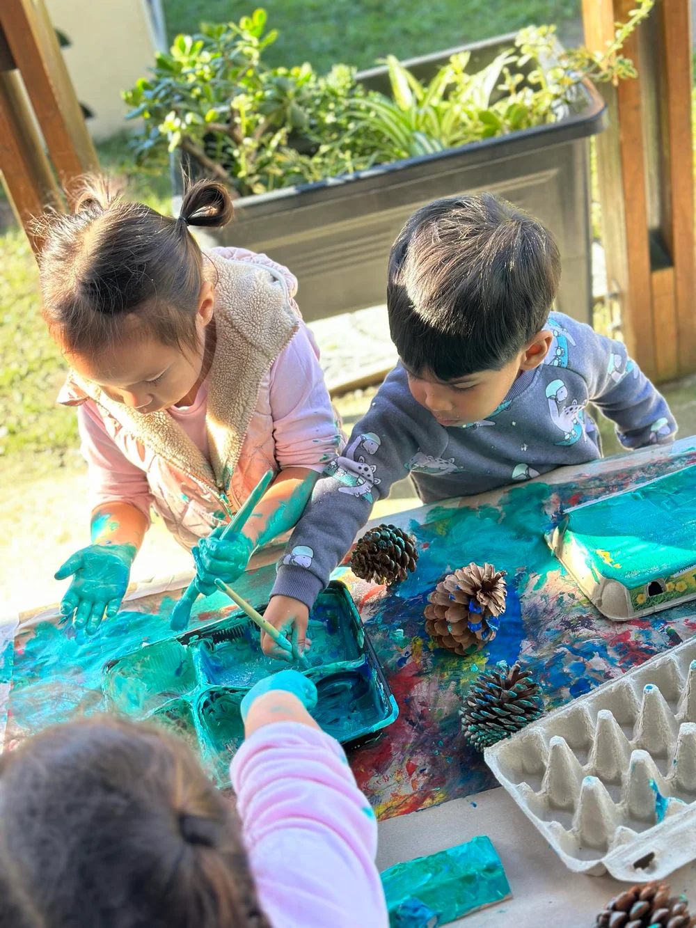 Kukupa tamariki exploring paint and natural materials together