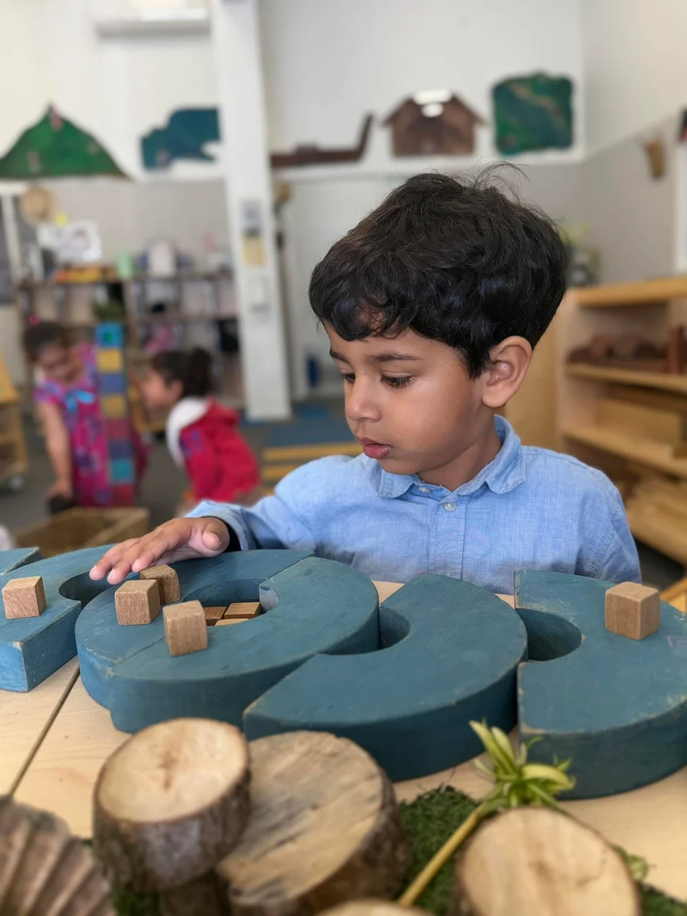 A Tiny Stars tamaiti concentrating on construction with wooden blocks