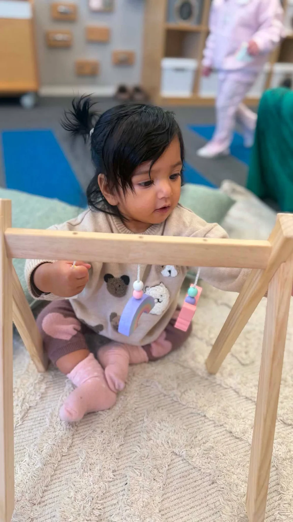 A Tavake infant exploring colourful hanging toys
